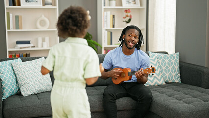 African american father and daughter playing ukulele dancing at home