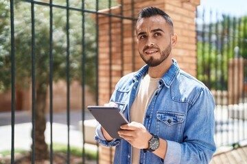 Young hispanic man smiling confident using touchpad at street