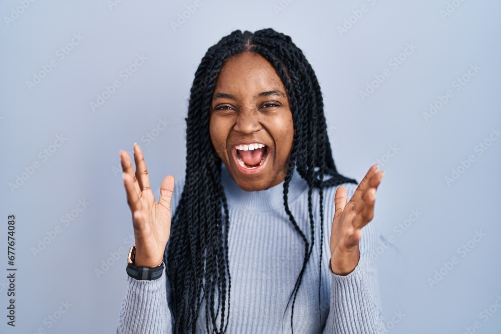 Sticker African american woman standing over blue background celebrating crazy and amazed for success with arms raised and open eyes screaming excited. winner concept