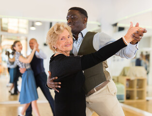 Man and senior woman dancing waltz in studio