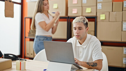 Obraz premium Two workers man and woman using laptop checking packages at office