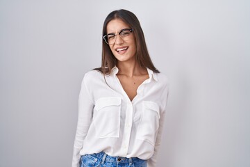 Young brunette woman wearing glasses winking looking at the camera with sexy expression, cheerful...