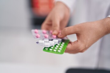 Young woman pharmacist holding pills tablets at pharmacy