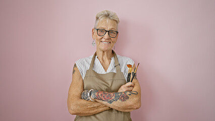 Smiling, confident grey-haired senior woman artist, glasses perched, crosses arms holding...