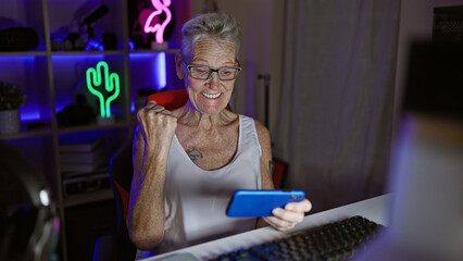 Epic win! grey-haired senior woman streamer, gaming guru, celebrates big win during late-night...