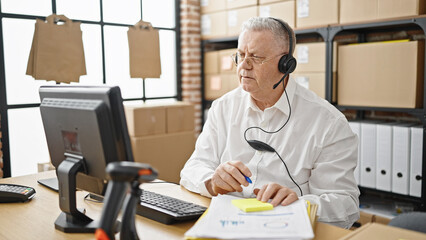 Middle age grey-haired man ecommerce business agent having video call writing on reminder paper at...
