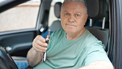 Middle age grey-haired man smiling confident holding key of new car at street
