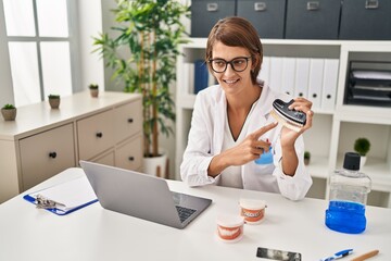 Young beautiful hispanic woman dentist smiling confident holding whitening test at clinic