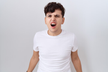 Obraz premium Young non binary man wearing casual white t shirt angry and mad screaming frustrated and furious, shouting with anger. rage and aggressive concept.