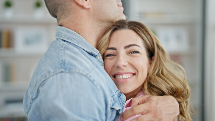 Man and woman couple hugging each other smiling at home
