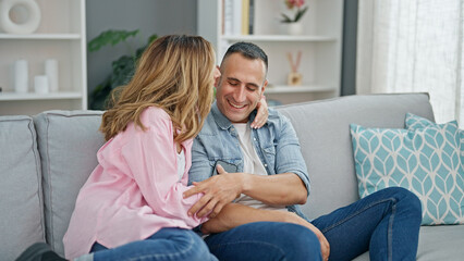 Man and woman couple hugging each other sitting on sofa at home