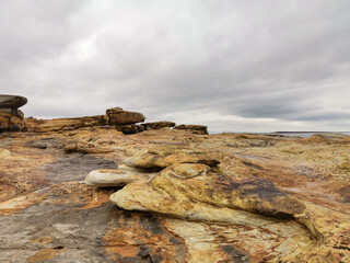 The shore of red stones next to the rocks are Two Brothers on the Fishing Peninsula. The picturesque shore of the harsh Barents Sea. The North of Russia. The Kola Peninsula. The Arctic