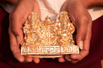 Golden God Ganesh and Lakshmi idol in hand after Diwali puja, close up photo - obrazy, fototapety, plakaty