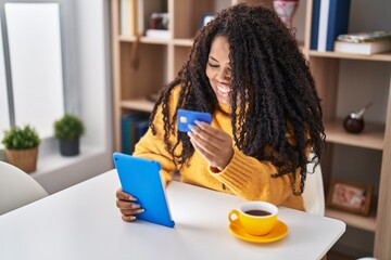 African american woman using touchpad and credit card sitting on table at home