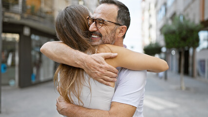 Confident father hugging his smiling daughter on a sunny street, sharing joy and happiness together
