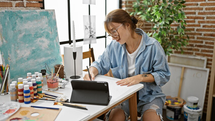 Young woman artist drawing on paper using touchpad at art studio