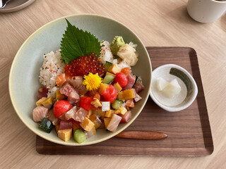 Japanese sashimi rice with salmon, toro, egg, cucumber, fish and other ingredient with rice donburi. Wasabi is on the side on a wooded tray.