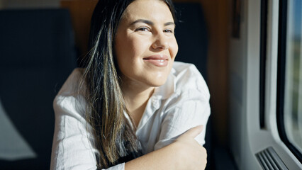 Young beautiful hispanic woman smiling happy looking through the window inside train wagon