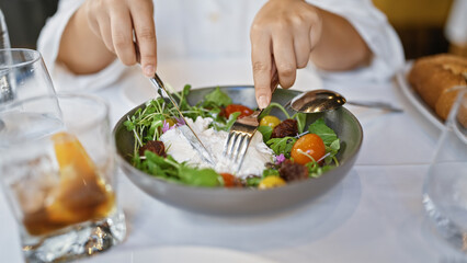 Young woman mixing burrata salad at the restaurant