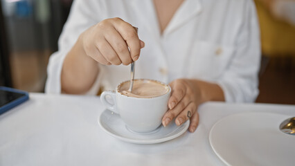 Young woman drinking coffee sitting on the table at the restaurant