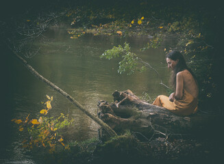 woman in yellow dress sitting on a log on the shore of a lake, Slovenia II