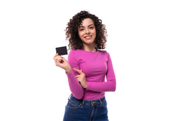 young well-groomed stylish curly brunette lady dressed in a purple turtleneck holds a credit card. e-business concept