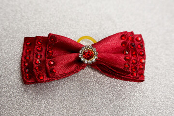 on a silver background lies a burgundy bow with shiny white to red stones in the middle. Christmas....