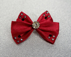 on a silver background lies a burgundy bow with shiny stones in the middle. Christmas. accessories