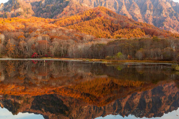 鏡池に映る朝日を浴びる紅葉の戸隠連山