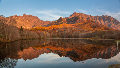 Fototapeta na wymiar 鏡池に映る朝日を浴びる紅葉の戸隠連山