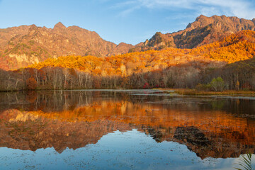 鏡池に映る朝日を浴びる紅葉の戸隠連山