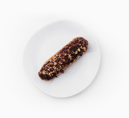 eclair with chocolate and nuts on a white plate