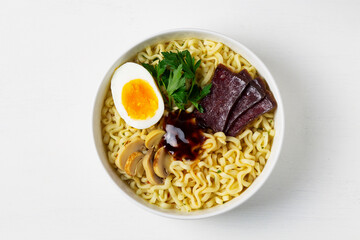 A bowl of Korean soup with food sticks. Japanese ramen noodles with chicken, boiled egg, mushrooms, spring onions and soy sauce. Traditional Asian cuisine. copy space. top view
