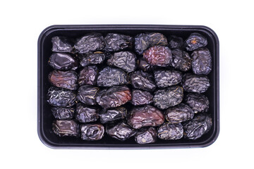 Close-up view of Black food container filled with Pile of large delicious Ajwa dates to keep food hygienic isolated on white background. Arabic healthy food concept.
