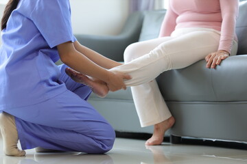 Physiotherapist nurse doing physiotherapy to rehabilitate leg of elderly female patient. - obrazy, fototapety, plakaty