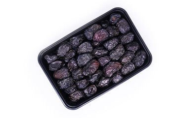 Close-up view of Black food container filled with a Pile of large delicious Ajwa dates to keep food hygienic isolated on white background. Arabic healthy food concept. Top view with copy space.