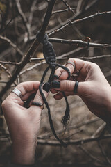 Female hands weaving a macrame braid on a tree branch