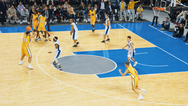 TV Broadcast Style Footage Of Basketball Championship in an Arena. Yellow Team Passing the Ball Between Teammates, Forward Player Aiming to Score a Two-Point Goal From a Distance. Sports Channel.