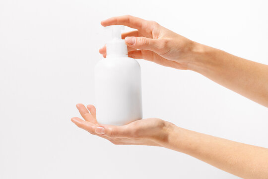 Female hands holding white mockup jar of body or face cream with dispenser on white isolated background. Concept of beauty products, nutrition and skin care. Image for your design