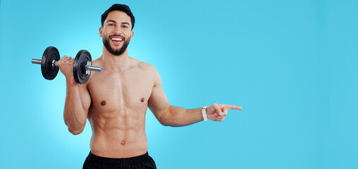 Gym, portrait and happy man with dumbbell or hand pointing to studio for fitness, promo or info on blue background. Face, smile and male bodybuilder show sign up, presentation or membership offer