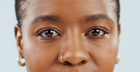 Fototapeta premium Eyes, looking and portrait of black woman in studio for vision, eyesight and focus on blue background. Healthcare, optometry and isolated face closeup of person with cosmetics, wellness and eye care