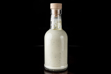 Bottle with tasty tartar sauce on black background