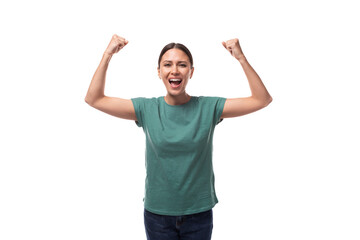 well-groomed slender young brunette woman dressed in a green T-shirt is emotionally aroused and raised her hands