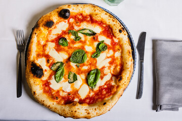 Pizza Margherita tradizionale napoletana con sugo di pomodoro, mozzarella e basilico fresco servita in una pizzeria elegante