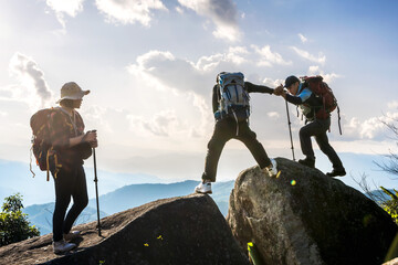 group of mountaineers people helping hands hiking to top of rock mountains - obrazy, fototapety, plakaty