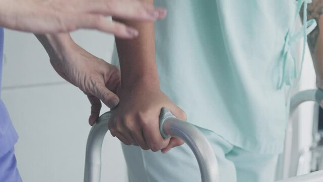 Close-up of sick woman hands using physical walker to learn to walk and with the help of doctor