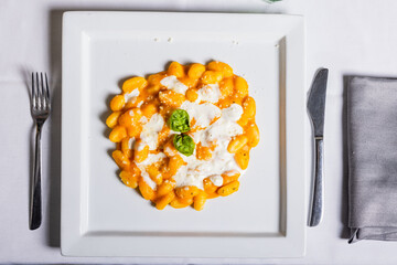 Piatto di gnocchi di patate con zucca, stracciata di bufala e basilico fresco serviti come primo...