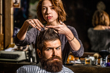 Working hair scissors. Professional barber girl cutting hair of bearded man. He is getting haircut at barbershop. Barbershop, beauty salon. Beard man in barbershop. Barber scissors, barber shop
