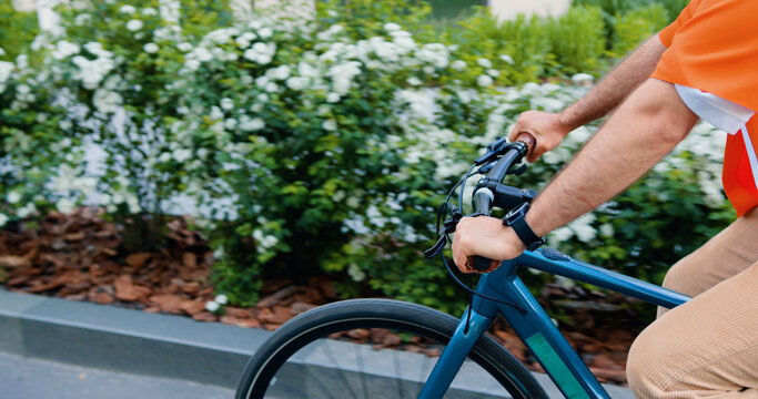 Happy bearded caucasian bearded man in headphone and sunglasses using smartphone while walking with bike at urban area. Commute work sustainable lifestyle in the city.