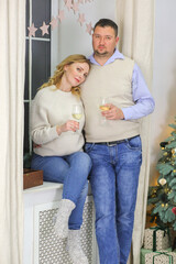 Loving couple with glasses of champagne near the window on New Year's Eve. Drinks concept